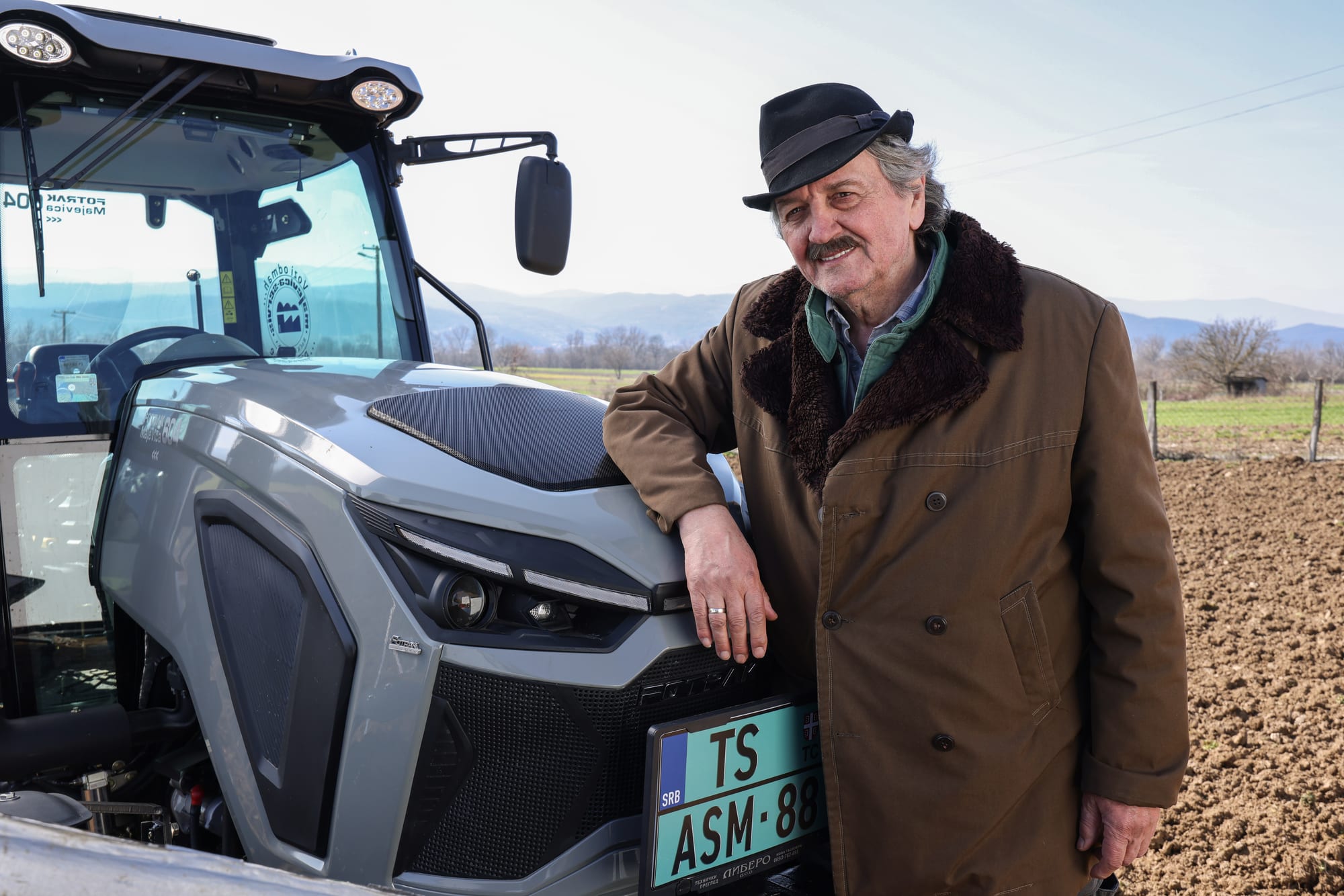 Poljoprivrednik uz traktor na njivi